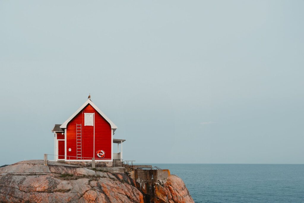 A red house on a rock by the ocean
