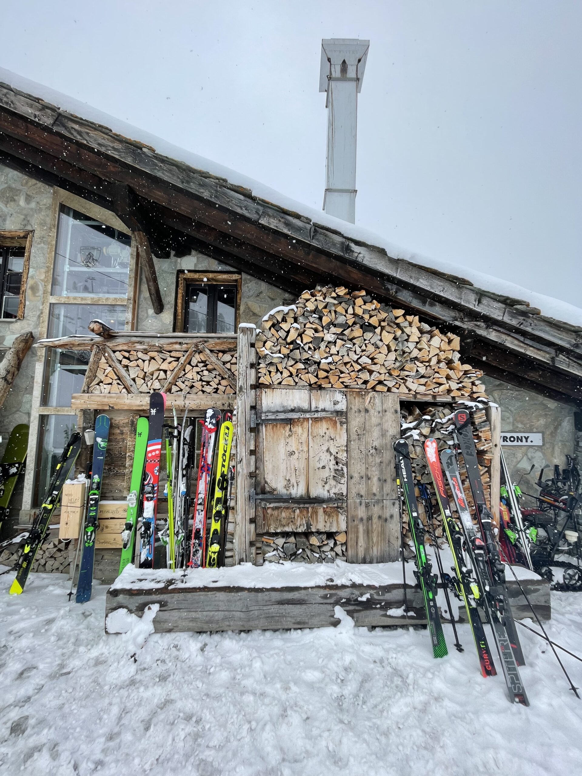 skis in front of a log pile at chez vrony on a snowy deck